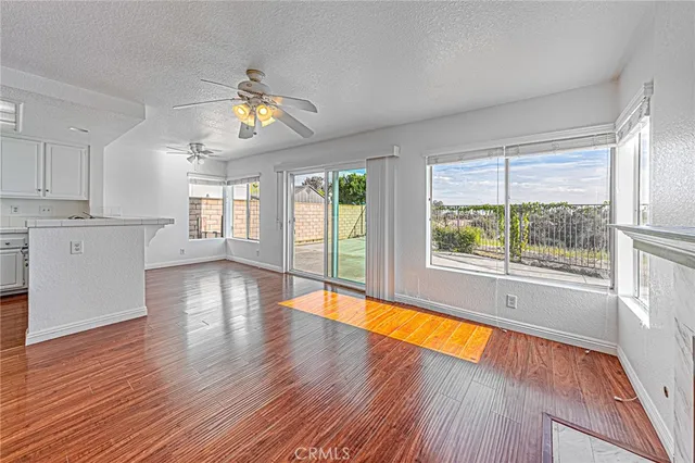 a living room with stainless steel appliances furniture wooden floor and a large window