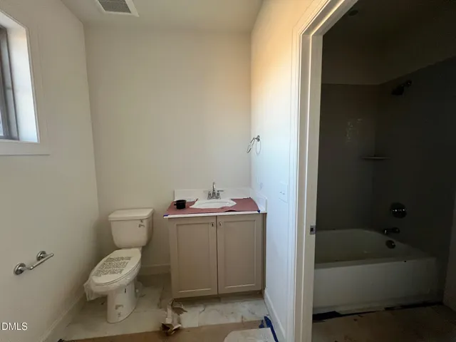 an empty room with wooden floor fireplace and windows