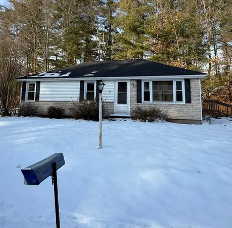 a front view of house with yard and trees in the background