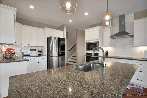 a kitchen with stainless steel appliances granite countertop a stove a sink a oven a dining table and chairs with wooden floor