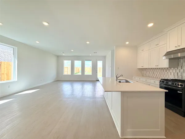 a large kitchen with stainless steel appliances a large counter top a stove a sink a refrigerator and a cabinets