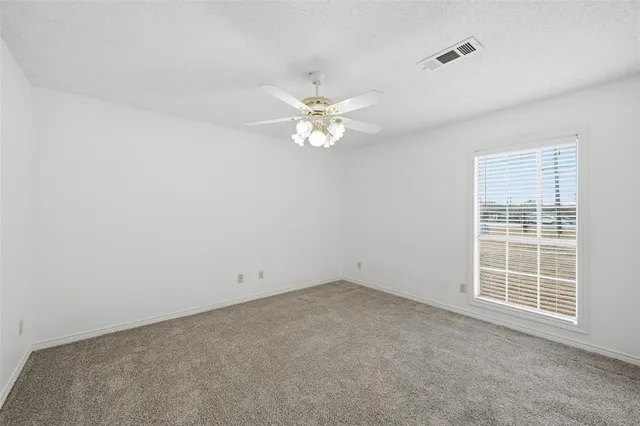an empty room with windows and fan