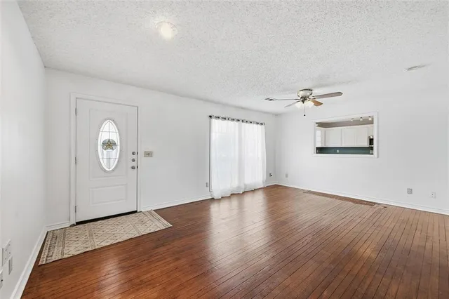 an empty room with wooden floor cabinet and windows