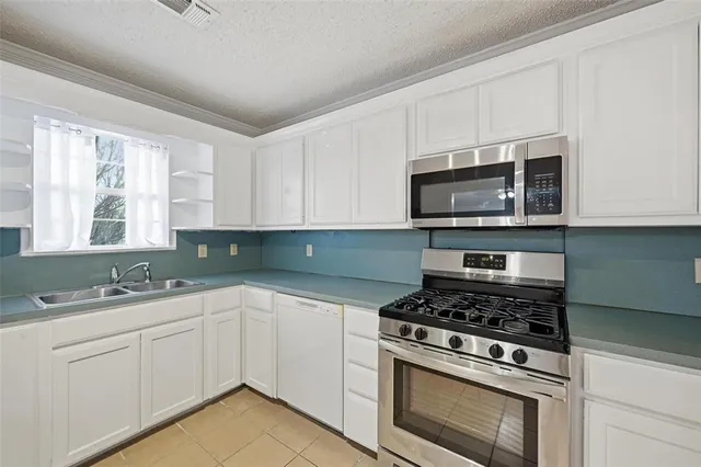 a kitchen with cabinets appliances a sink and a window
