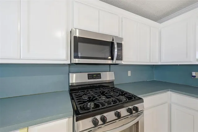 a kitchen with stainless steel appliances granite countertop white cabinets and a stove top oven