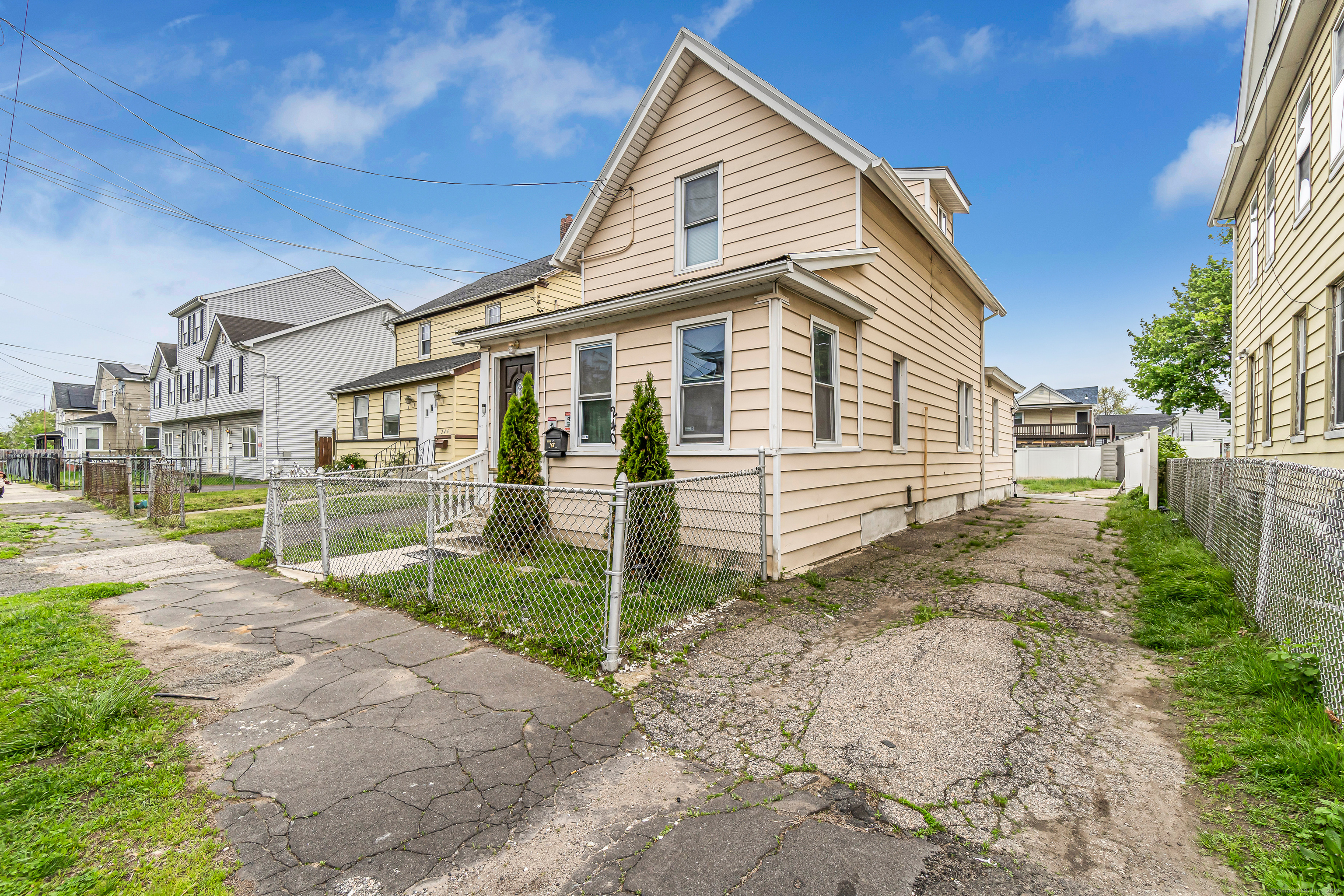 a view of a white house next to a yard with potted plants