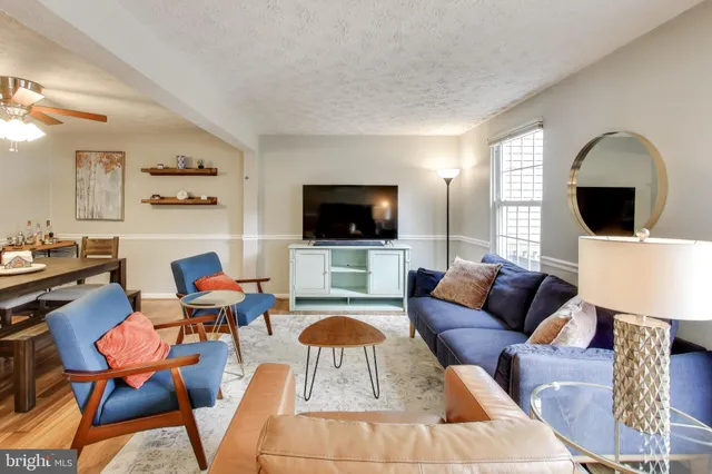 a living room with furniture a flat screen tv and kitchen view