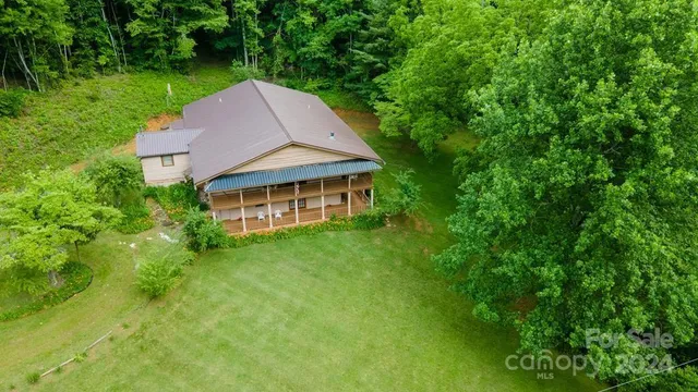 a view of a house with a big yard plants and large trees