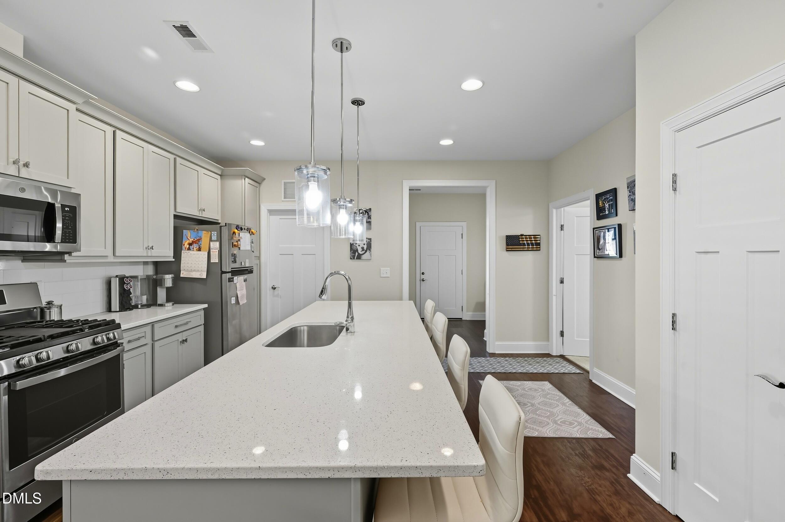 116 Beaufort Loop Clayton, NC 27520 - Photo 7 of 33 a kitchen with stainless steel appliances kitchen island granite countertop a refrigerator a stove a sink a microwave oven with white cabinets and wooden floor