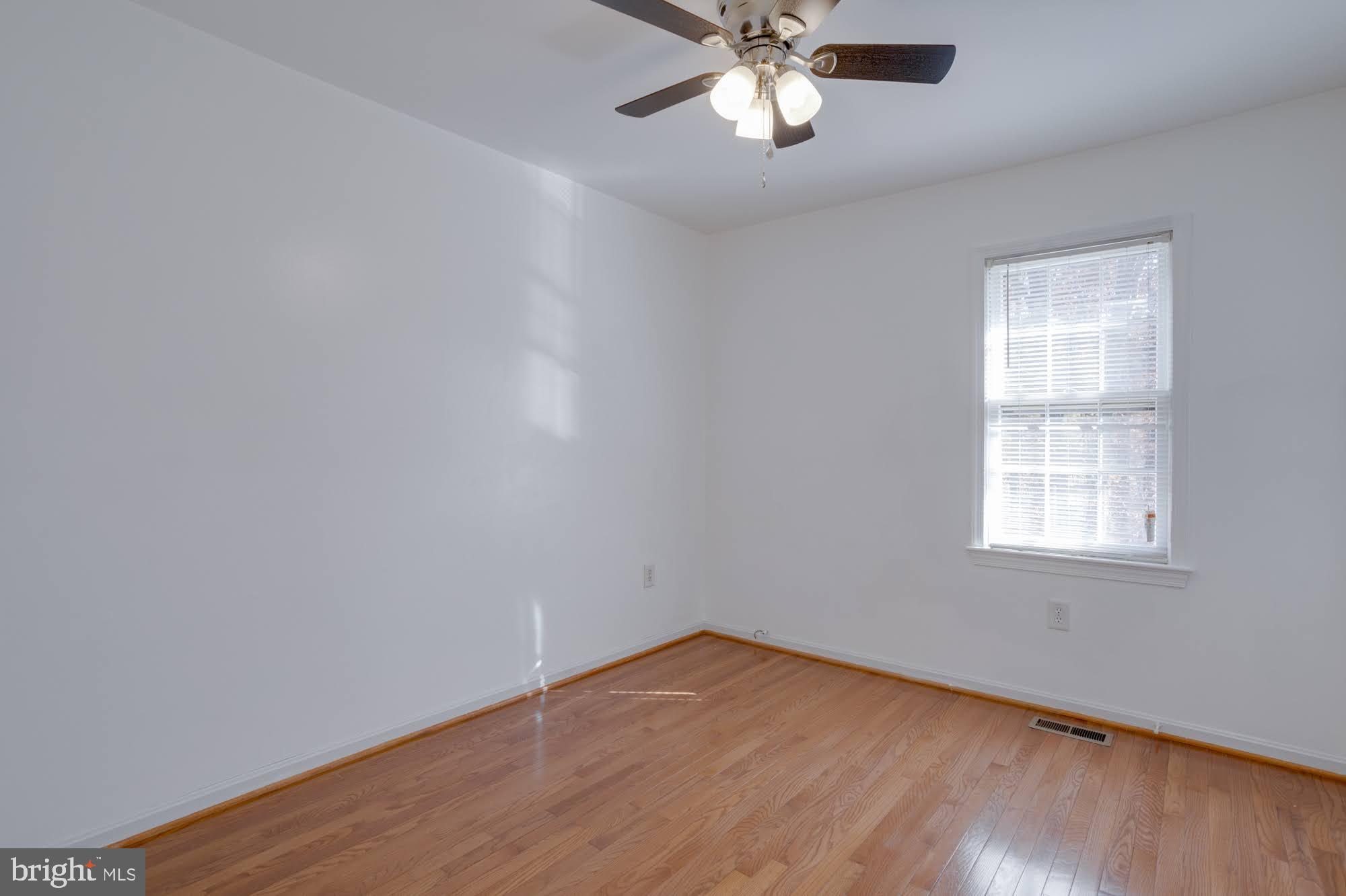 9043 Blarney Stone Drive Springfield, VA 22152 - Photo 17 of 23 an empty room with wooden floor chandelier fan and windows
