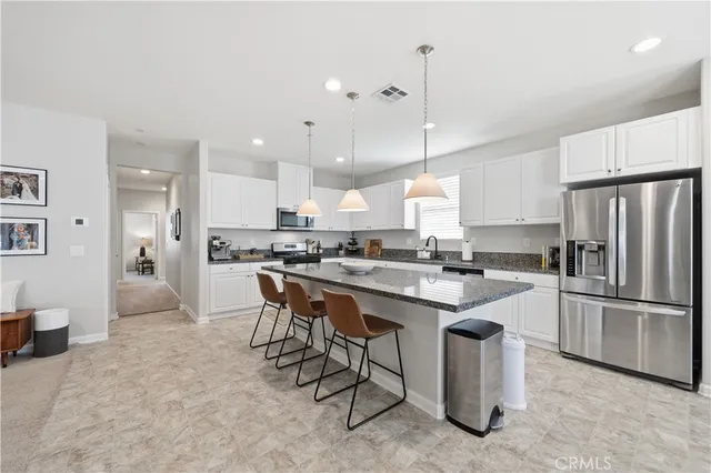 a large white kitchen with a refrigerator a stove top oven a sink and cabinets