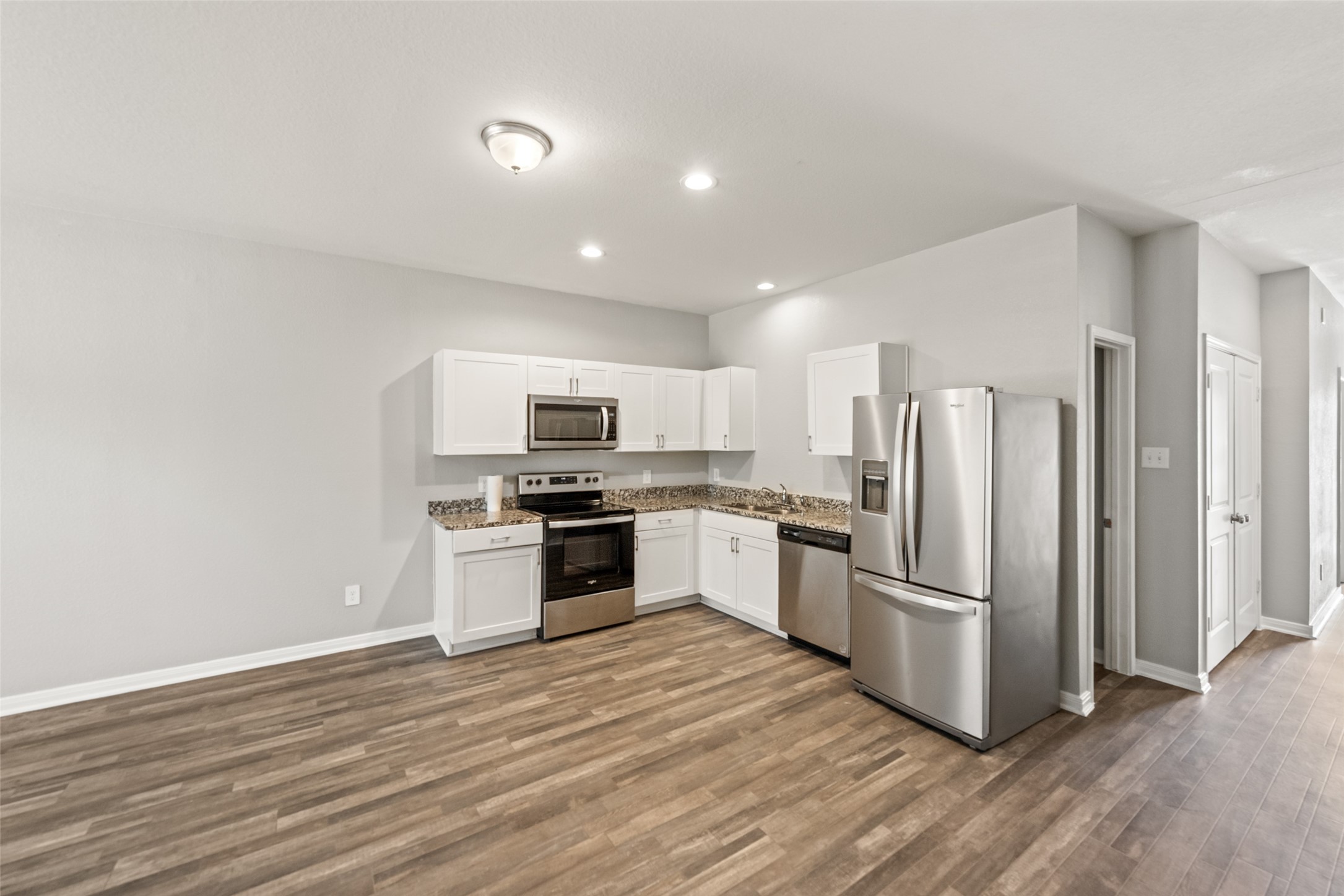 Open-concept living, dining, and kitchen area featuring durable flooring, recessed lighting, and a bright, modern layout.