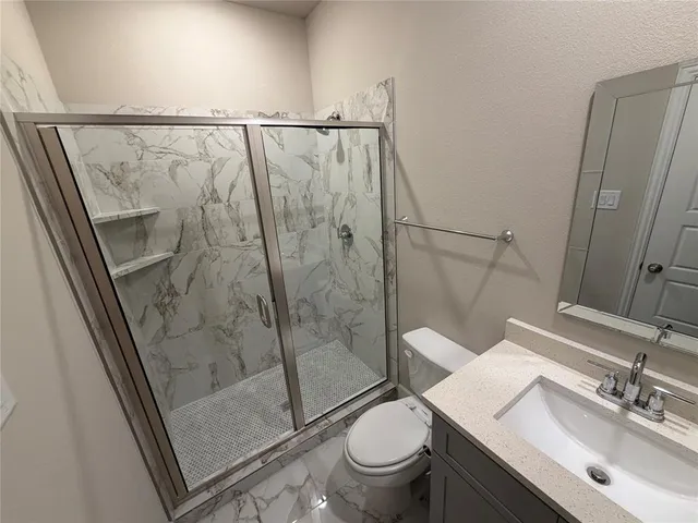 a bathroom with a granite countertop sink toilet and shower