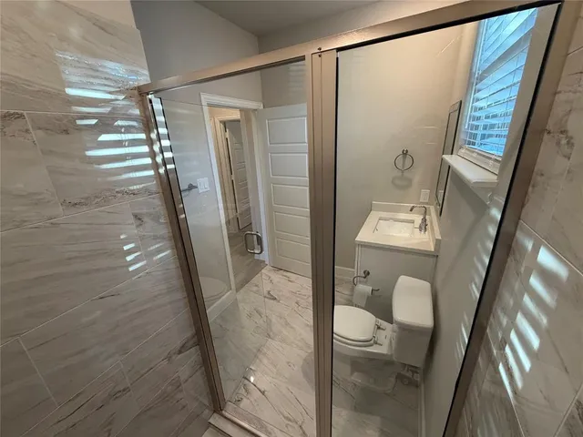 a bathroom with a glass door shower and toilet