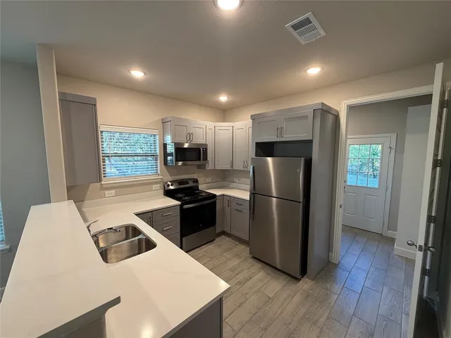 a kitchen with stainless steel appliances a stove a refrigerator a sink a oven with wooden floor and cabinets