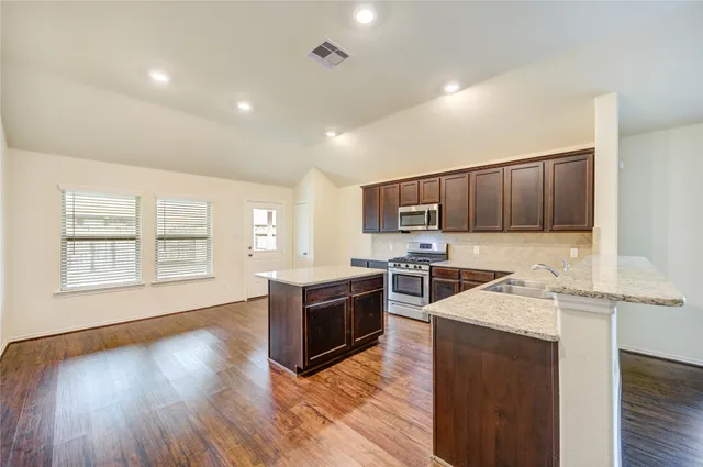 a view of an empty room with wooden floor and a ceiling fan