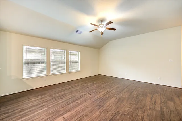 a view of empty room with wooden floor and fan