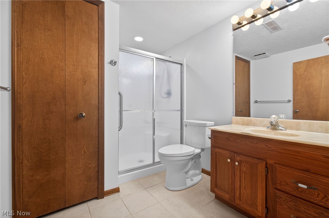 5346 Burlawn Street Northwest Canton, OH 44708 - Photo 31 of 40 Bathroom featuring a shower with sliding glass doors, a white toilet, and a wood-finish vanity with a single sink and light-colored countertop