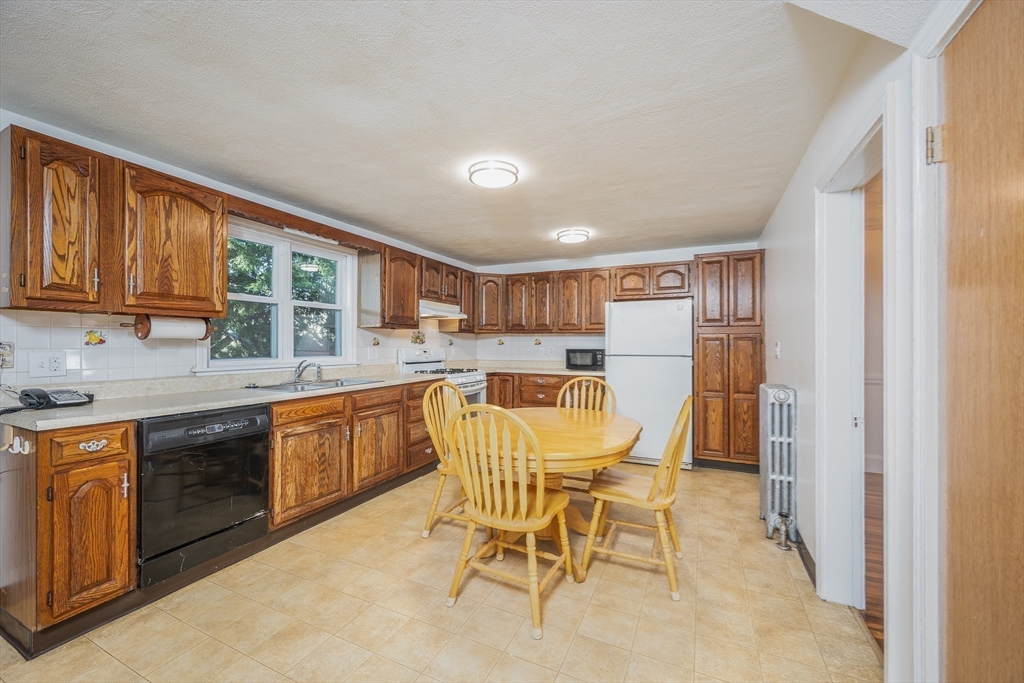 10 Weston Street Milton, MA 02186 - Photo 13 of 35 a kitchen with a table chairs refrigerator and cabinets