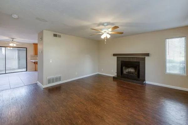 an empty room with wooden floor fireplace and a window