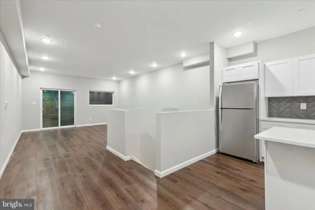 an empty room with wooden floor and a kitchen