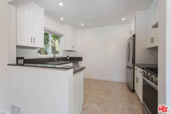 a kitchen with stainless steel appliances granite countertop a sink a stove a refrigerator and a window