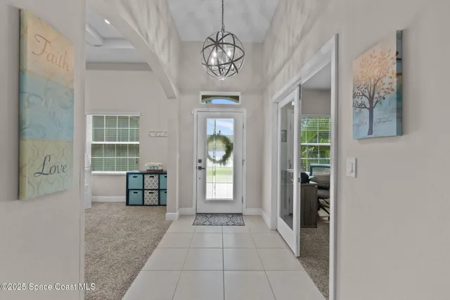 a living room with furniture kitchen view and a chandelier