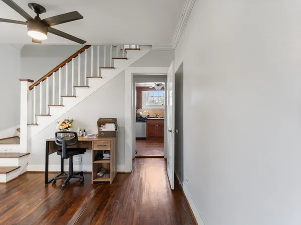 a view of a hallway to a livingroom with wooden floor and furniture