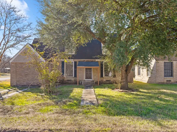 a view of a house with a yard and large tree