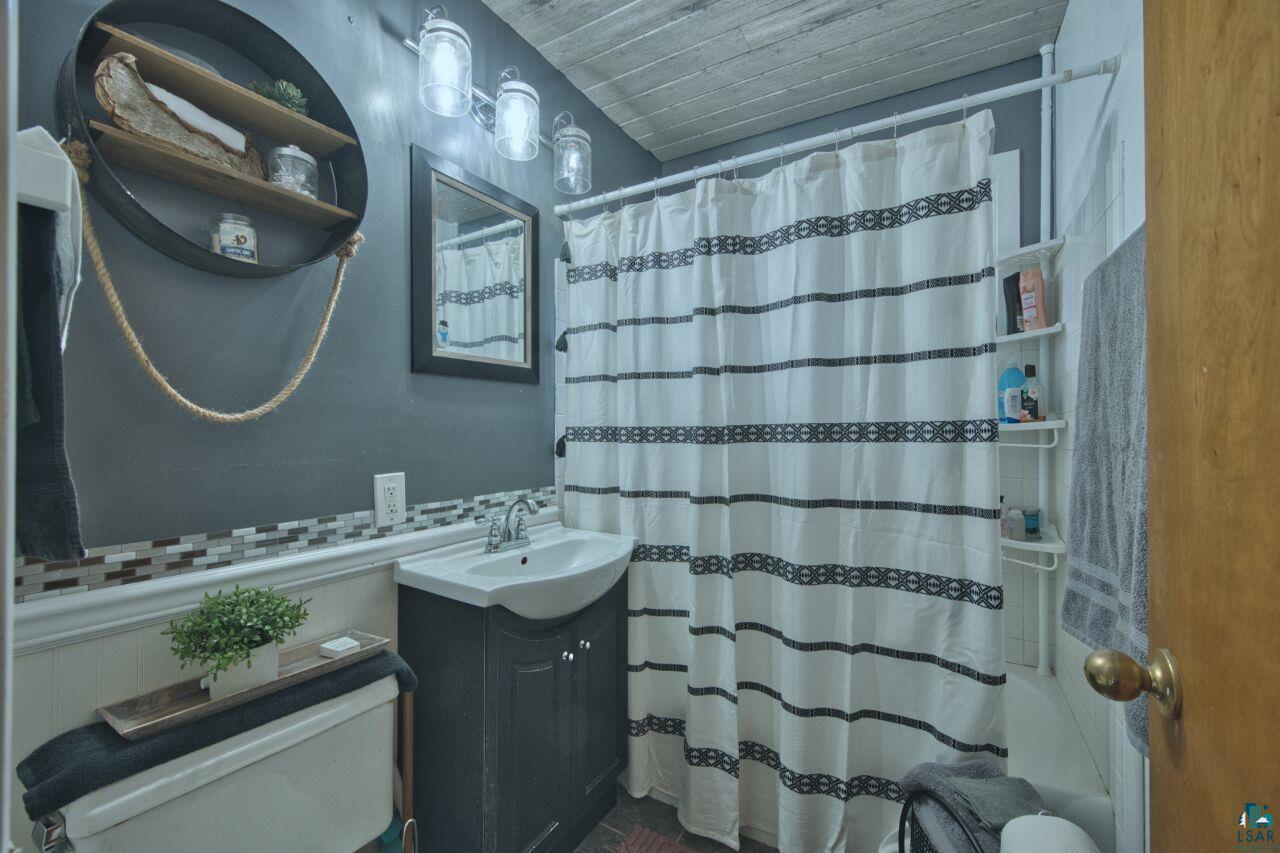 329 Wyandotte Road Hoyt Lakes, MN 55750 - Photo 15 of 52 Bathroom featuring a dark wood-finish vanity with an integrated sink, mosaic tile backsplash, and overhead vanity lighting