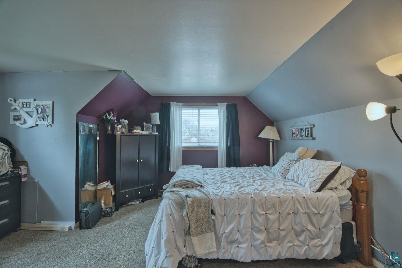 329 Wyandotte Road Hoyt Lakes, MN 55750 - Photo 22 of 52 Carpeted bedroom featuring an angled ceiling design, a window with blinds, and contrasting wall colors