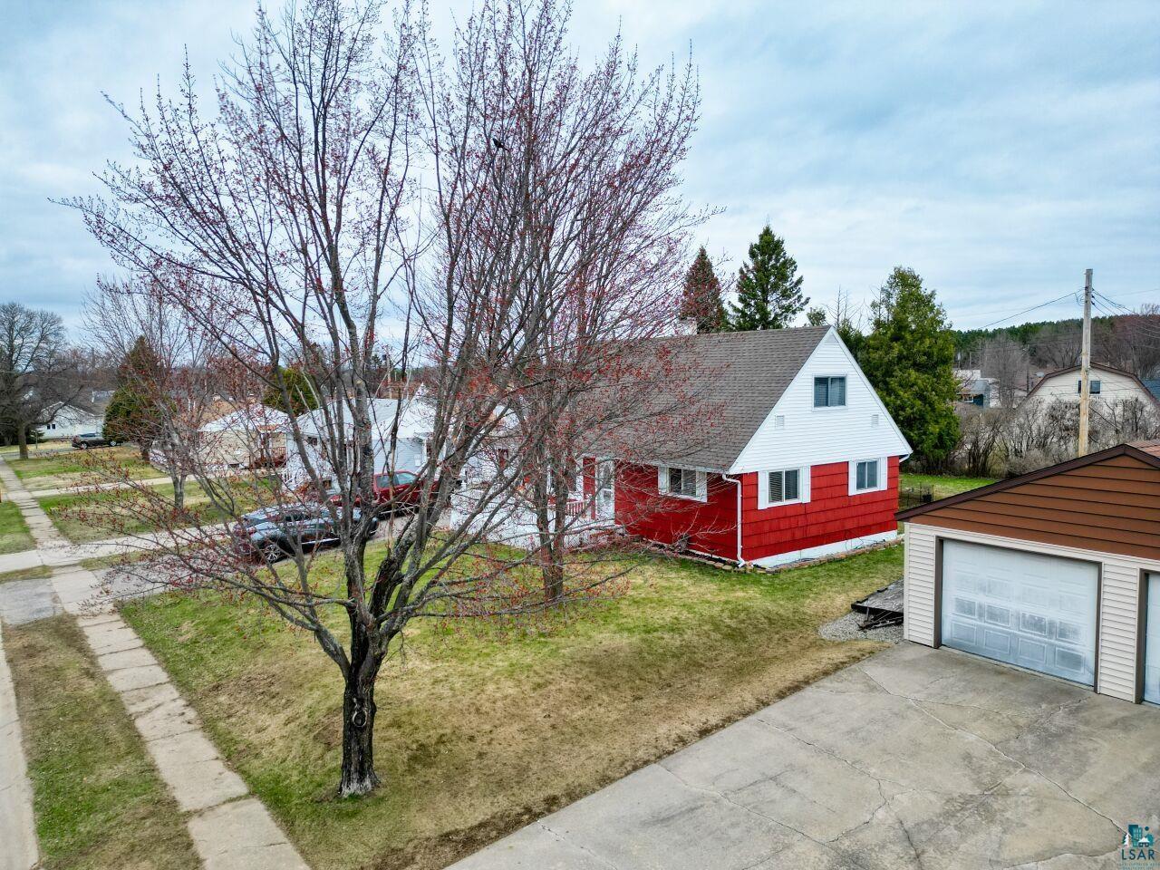 329 Wyandotte Road Hoyt Lakes, MN 55750 - Photo 46 of 52 Red-sided residence with a white-trimmed gable roofline, featuring white window frames and a prominent attached two-car garage with a brown-trimmed roof