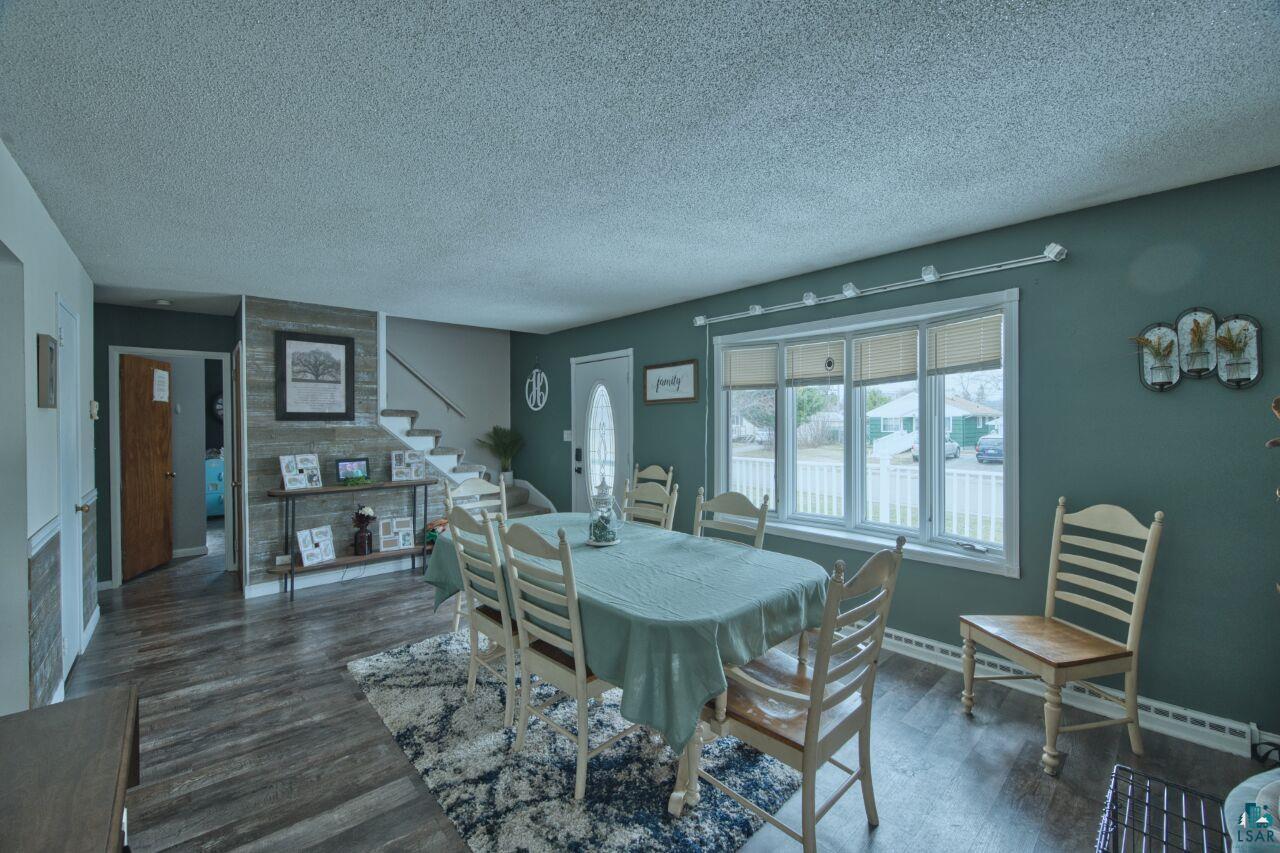 329 Wyandotte Road Hoyt Lakes, MN 55750 - Photo 6 of 52 Spacious dining area featuring wood-finish flooring, a bay window with white trim, and a staircase with white risers and handrail