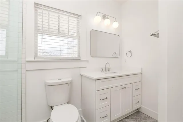 a bathroom with a toilet a sink a vanity a window and mirror