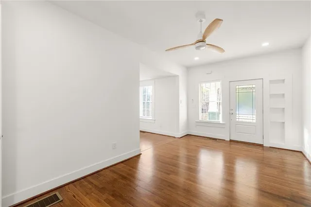 a view of an empty room with wooden floor and a window