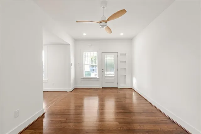 a view of an empty room with a window and wooden floor
