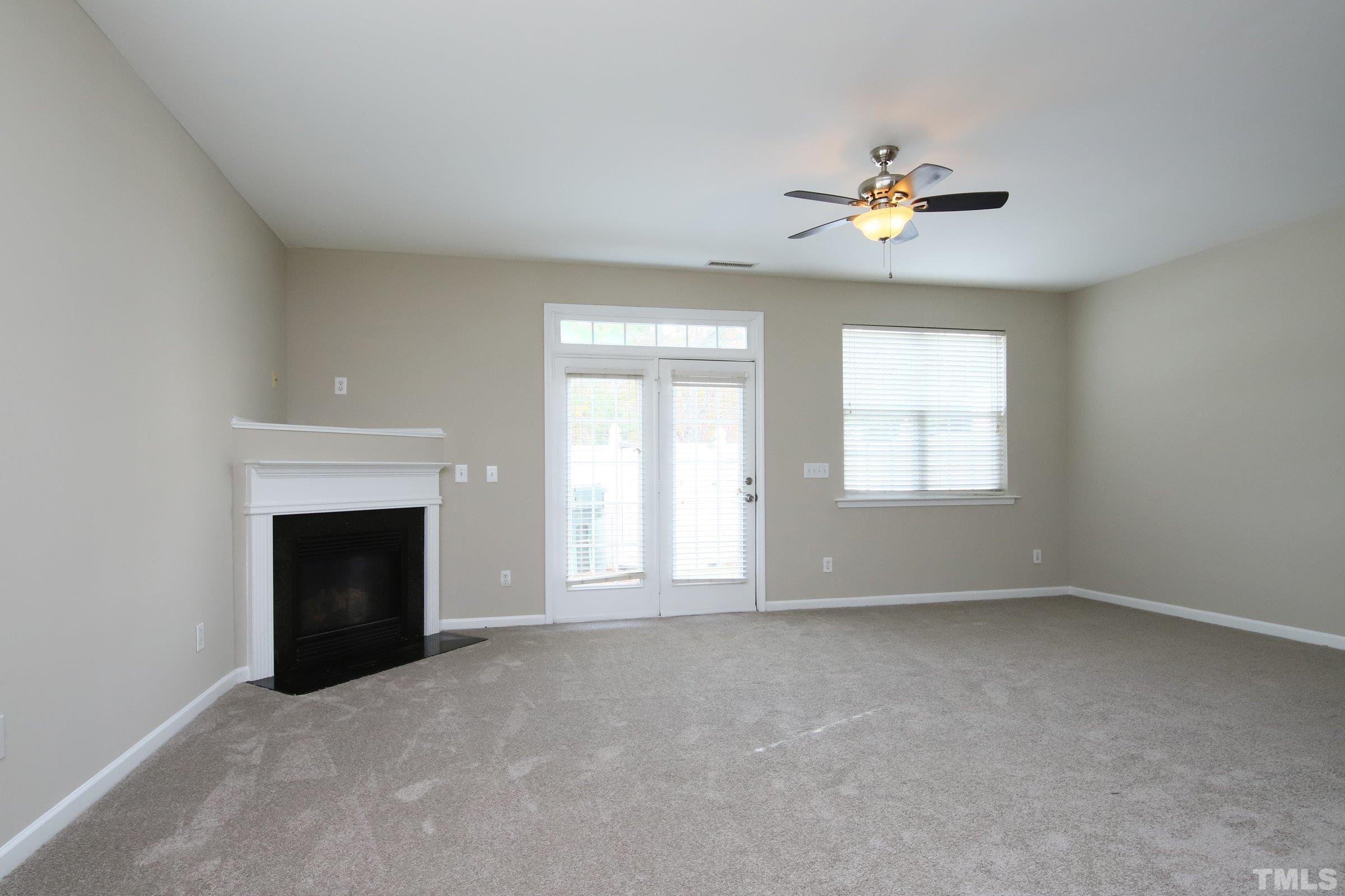 8205 Martello Lane Raleigh, NC 27613 - Photo 10 of 28 a view of an empty room with chandelier fan and fire place