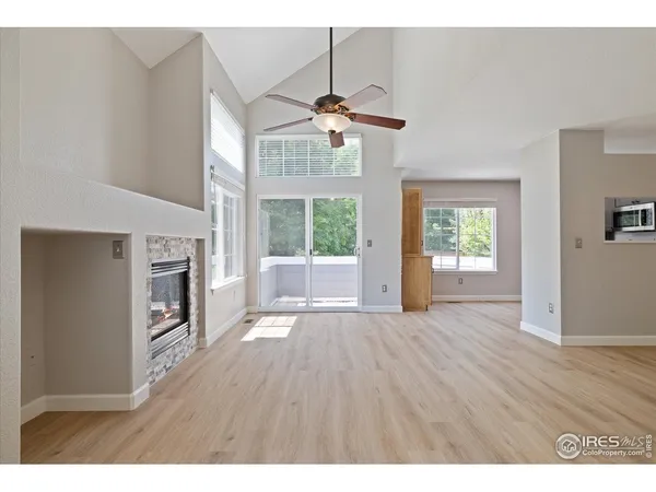 a view of a livingroom with wooden floor a ceiling fan and windows