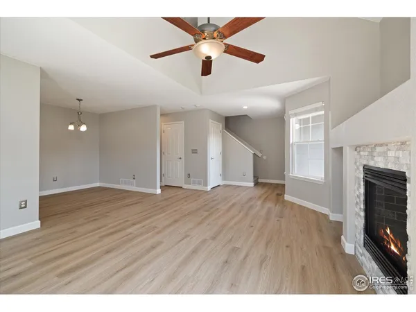 a view interior of a house with wooden floor a fireplace and a ceiling fan