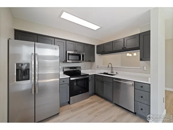 a kitchen with stainless steel appliances kitchen island granite countertop a refrigerator and a sink