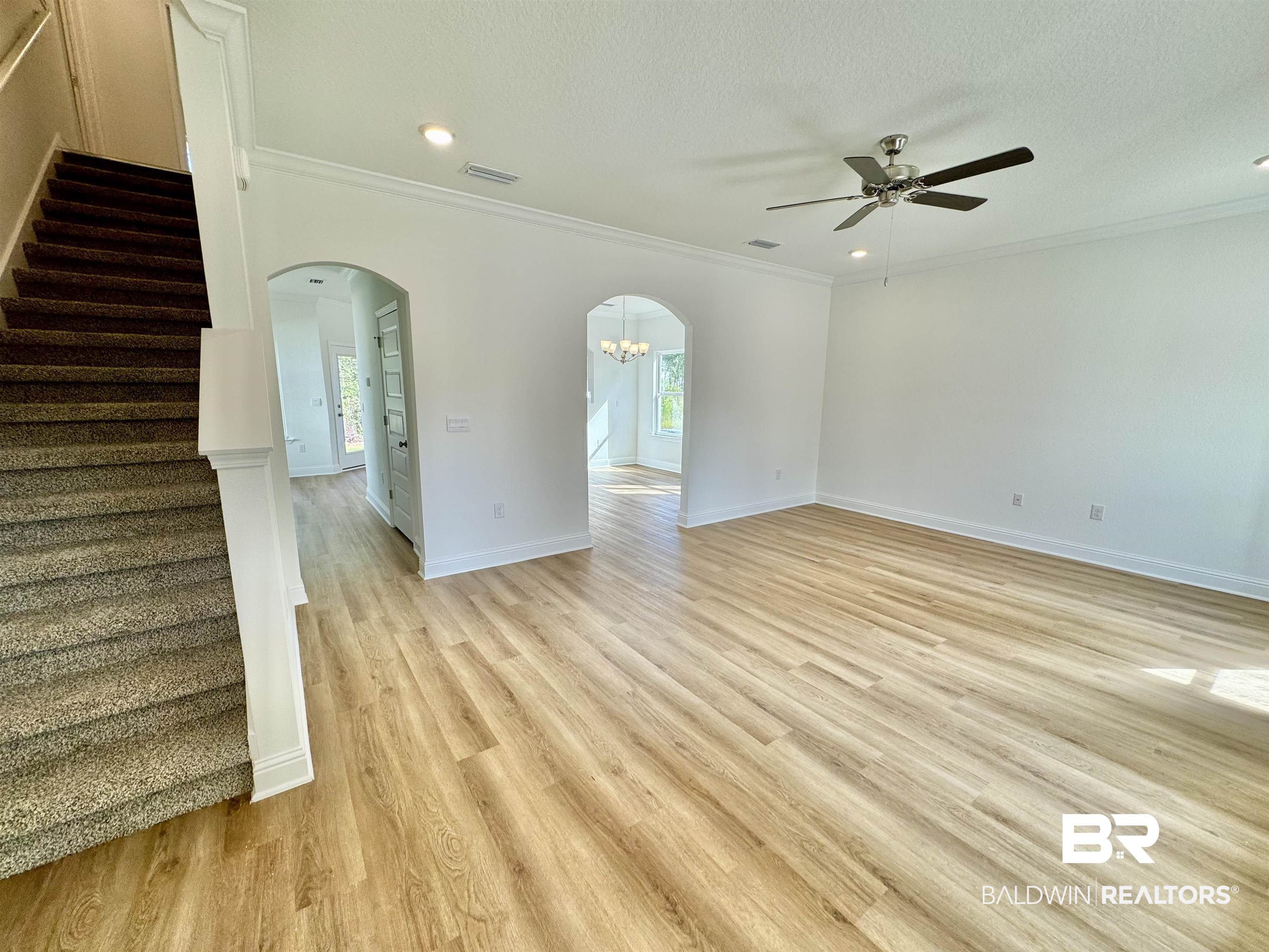 27491 Canal Road Orange Beach, AL 36561 - Photo 8 of 20 Unfurnished room featuring ceiling fan with notable chandelier, a textured ceiling, light hardwood / wood-style flooring, and ornamental molding
