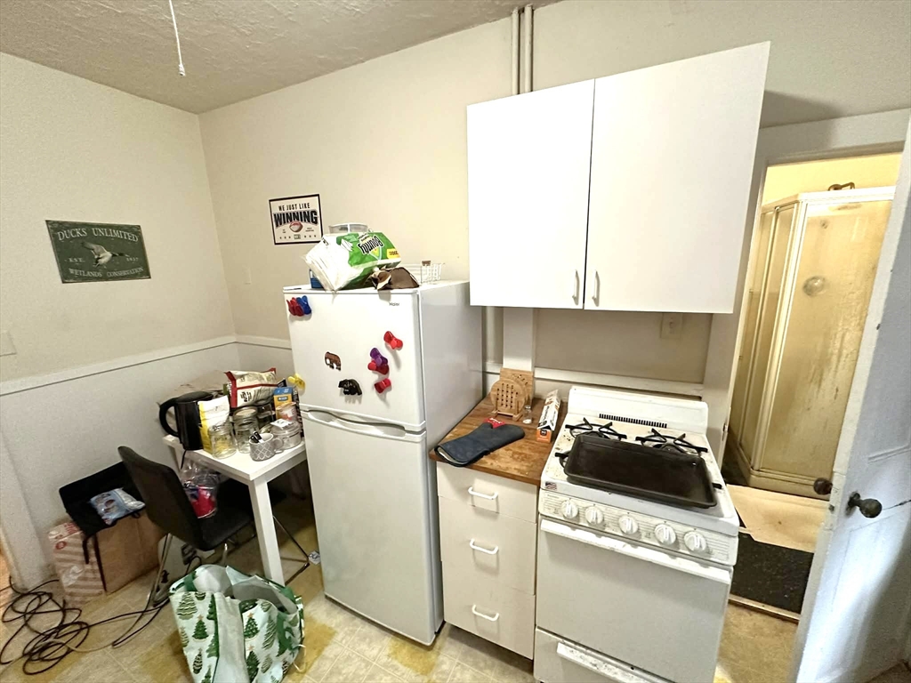 83 Charles Street, Unit 1 Boston, MA 02114 - Photo 7 of 11 a kitchen with a stove and a white refrigerator