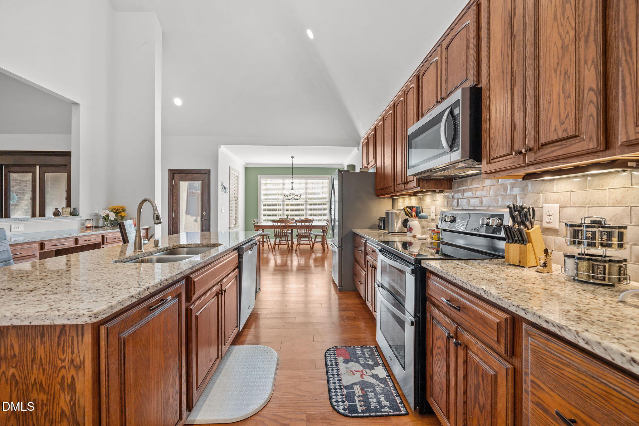 868 Julie McKnight Road Kittrell, NC 27544 - Photo 16 of 54 a kitchen with stainless steel appliances granite countertop a sink a stove top oven a dining table and chairs with wooden floor