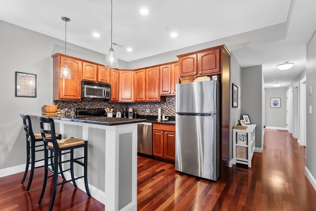 34 H Street, Unit 2L Boston, MA 02127 - Photo 7 of 20 a kitchen with stainless steel appliances granite countertop a refrigerator a stove top oven a sink dishwasher and wooden cabinets