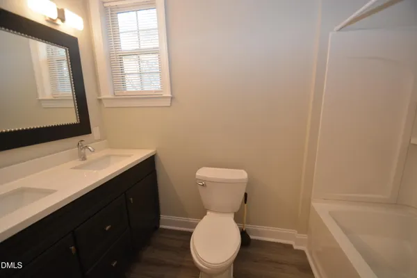 a bathroom with a toilet a sink a mirror and a window