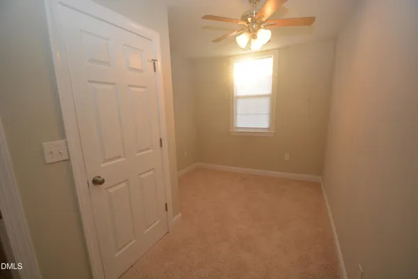an empty room with windows and fan