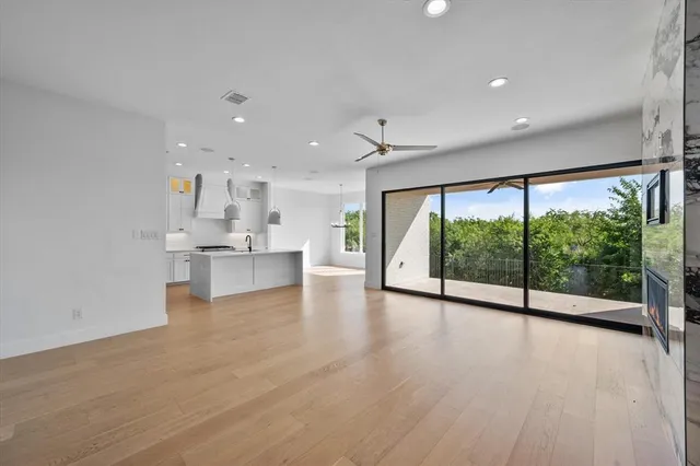a view of an empty room with wooden floor and a kitchen