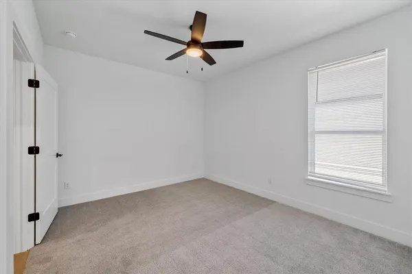 an empty room with a window and a ceiling fan