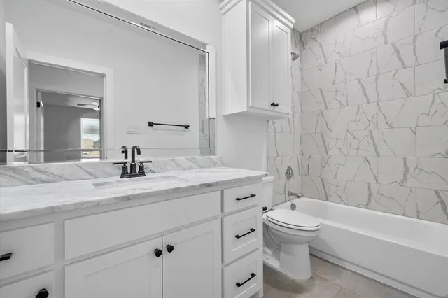 a bathroom with a granite countertop toilet a sink and a bathtub