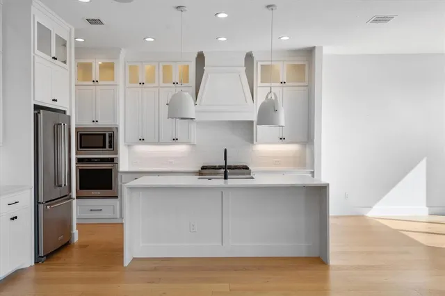 a kitchen with kitchen island a counter top space cabinets and stainless steel appliances